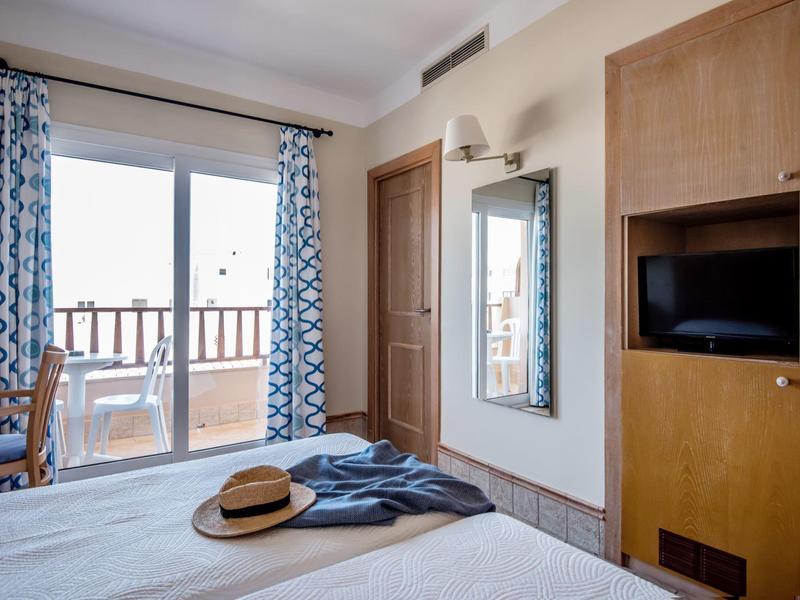 Hotelový pokoj s postelí, dřevěnou skříní, balkonem a výhledem ven.