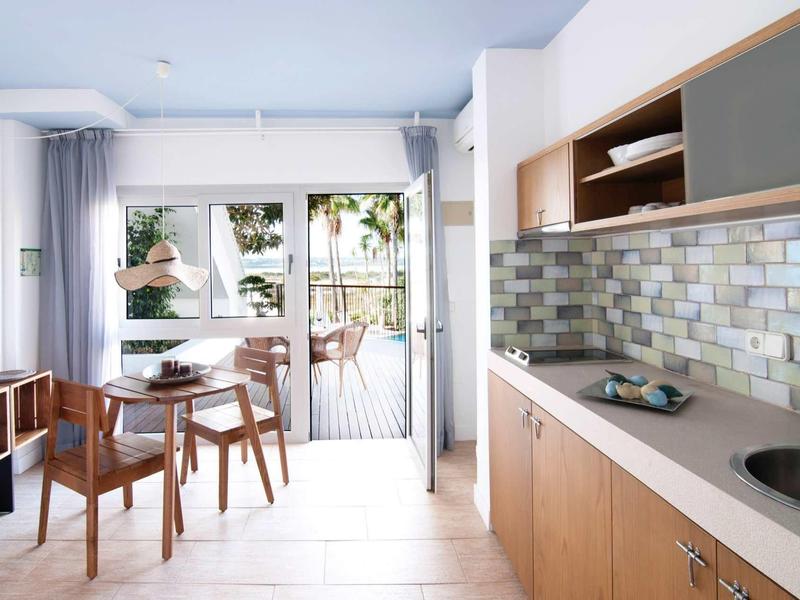 Helle Küche mit Holzschränken, Mosaikfliesen und Glas-Schiebetür zum grünen Balkon.