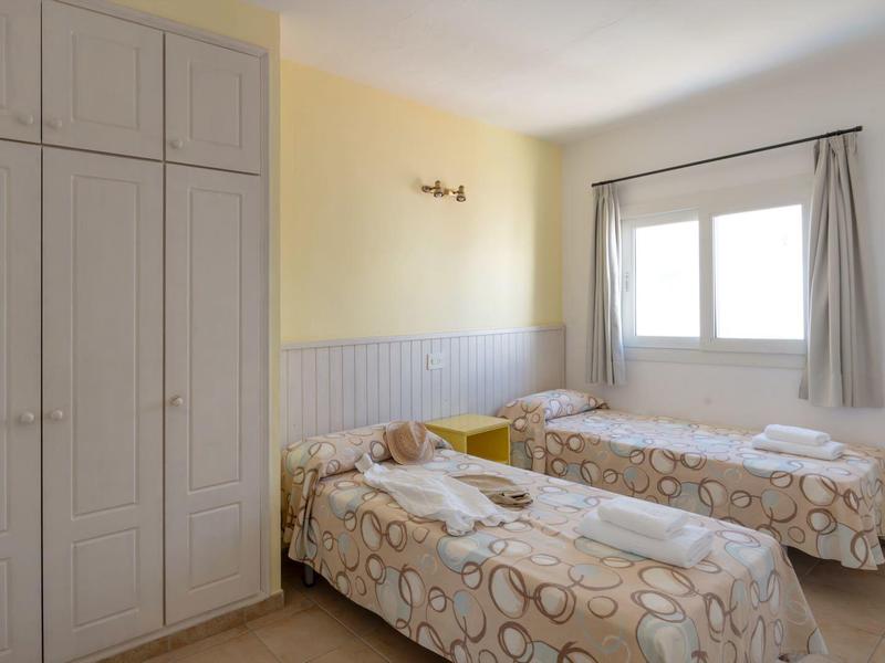 Twin room with wardrobe, windows, and light-colored walls in the hotel