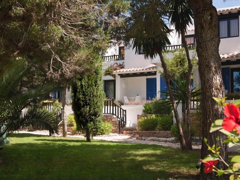 Dom z niebieskimi drzwiami i oknami otoczony drzewami i zielonym trawnikiem.