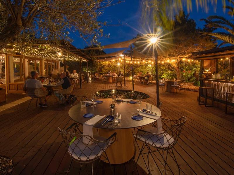 Przytulna restauracja na świeżym powietrzu z okrągłymi stolikami i ciepłym oświetleniem nocą