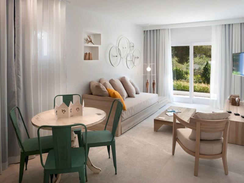 Jasny salon z dużym oknem, sofą, jadalnią i nowoczesnym wystrojem.