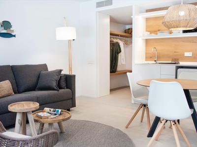 Modern eingerichtetes Wohnzimmer mit grauem Sofa, runden Holztischen und angrenzendem Essbereich.