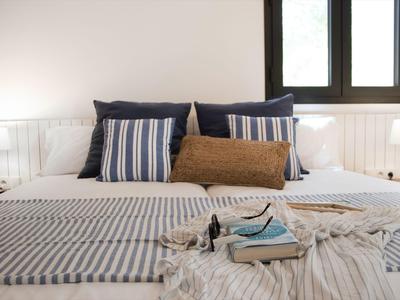 Gemütlich eingerichtetes Schlafzimmer mit gestreiften Decken und Kissen sowie Büchern auf dem Bett.