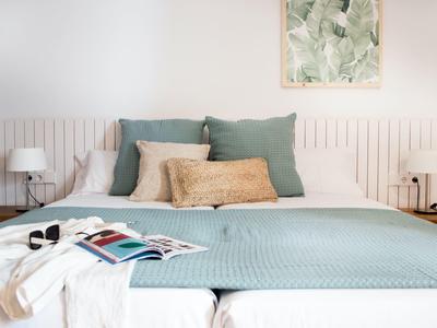 Przytulne podwójne łóżko z niebieskim narzutem, poduszkami i dekoracją ścienną w nowoczesnej sypialni.