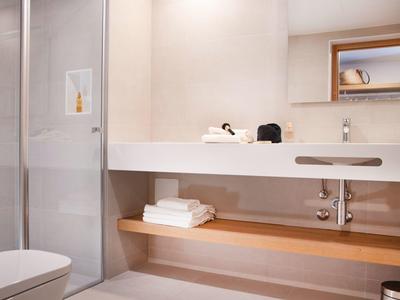 Nowoczesna łazienka z prysznicem, toaletą, umywalką i ręcznikami w drewnianych i białych tonach.