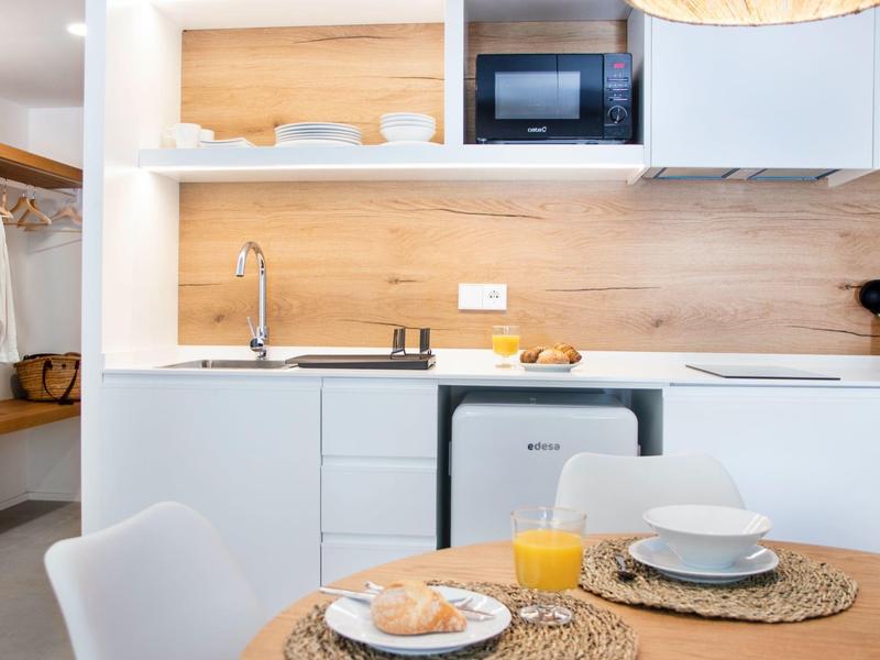 Nowoczesna mała kuchnia z białą szafką, mikrofalówką i stołem śniadaniowym