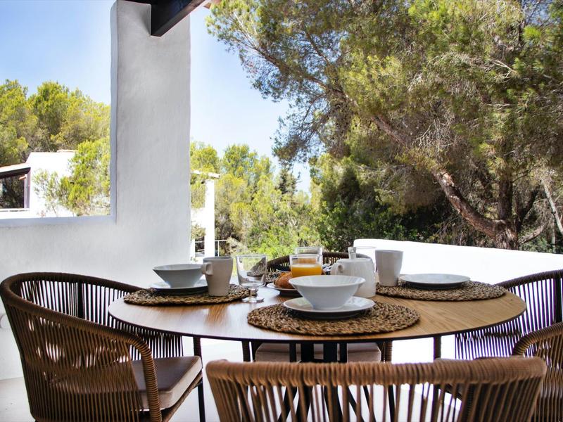 Taras ze stołem, krzesłami i śniadaniem z widokiem na drzewa i niebieskie niebo