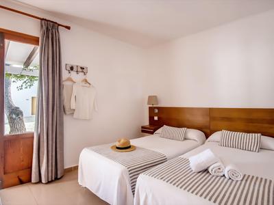 Hell möbliertes Hotelzimmer mit zwei Einzelbetten und Zugang zu einer Terrasse.