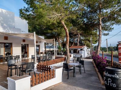 Moderner Außenbereich eines Cafés mit Sitzgelegenheiten und Bäumen im Hintergrund.