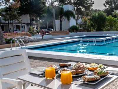 Mesa con desayuno y dos jugos de naranja junto a una piscina exterior limpia.