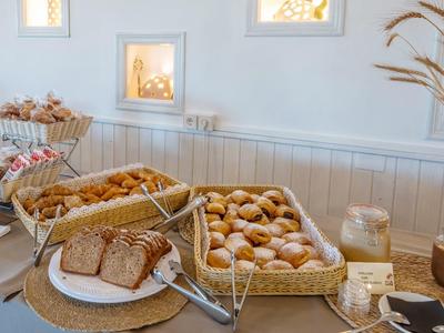 Un buffet de desayuno con pan, bollos y cereales en una habitación luminosa.