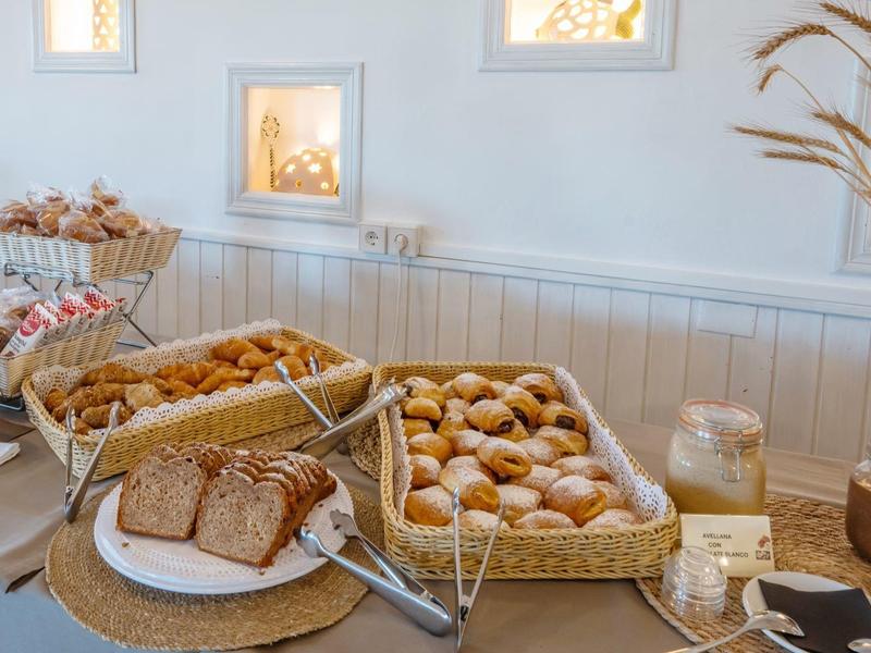 Un buffet de desayuno con pan, bollos y cereales en una habitación luminosa.