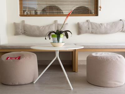 Cozy seating area with sofa, two gray poufs, and a round white table with a plant.