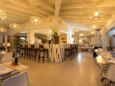 Modern designed hotel bar with high stools, round lights, and large windows.