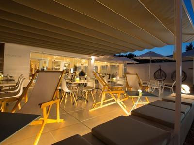 Illuminated terrace bar with lounge chairs and tables at dusk.