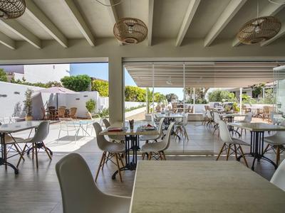 Modern open café or restaurant terrace with chairs and tables under a covered area.