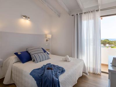 Modern hotel room with double bed, white walls, and view of a balcony