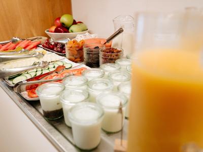 Frisches Frühstücksbuffet mit Joghurt, Obstsalat und Orangensaft in Gläsern.