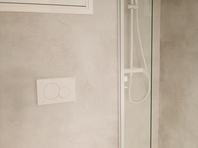 Modernes, schlichtes Badezimmer mit Toilette und begehbarer Dusche mit Glasabtrennung.