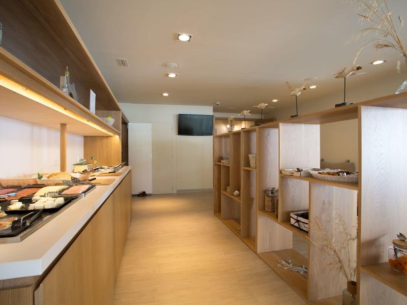 Modern breakfast room with buffet and seating areas in light wood design.