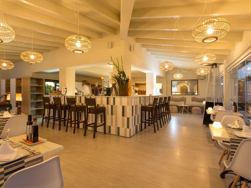 Modern designed hotel bar with high stools, round lights, and large windows.