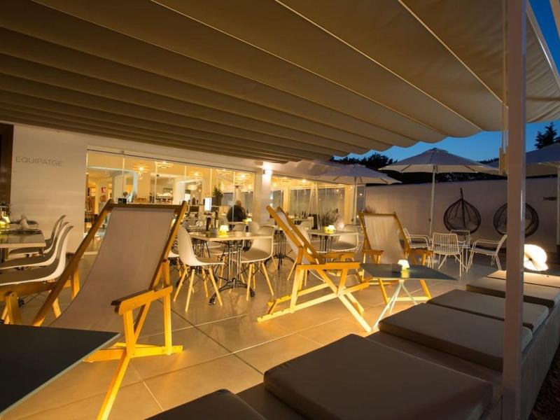 Illuminated terrace bar with lounge chairs and tables at dusk.