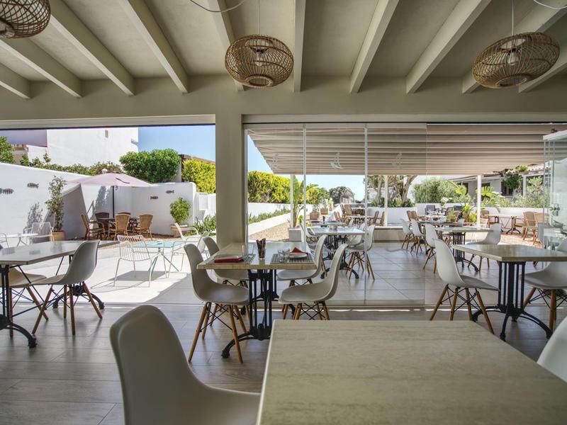 Modern open café or restaurant terrace with chairs and tables under a covered area.