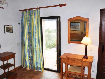 Lichte hotelkamer met houten meubels, kast, bureau en uitzicht op het balkon.