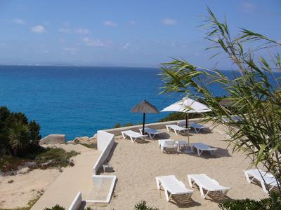 Strandbereich mit Liegestühlen, Sonnenschirmen und Blick auf das blaue Meer.