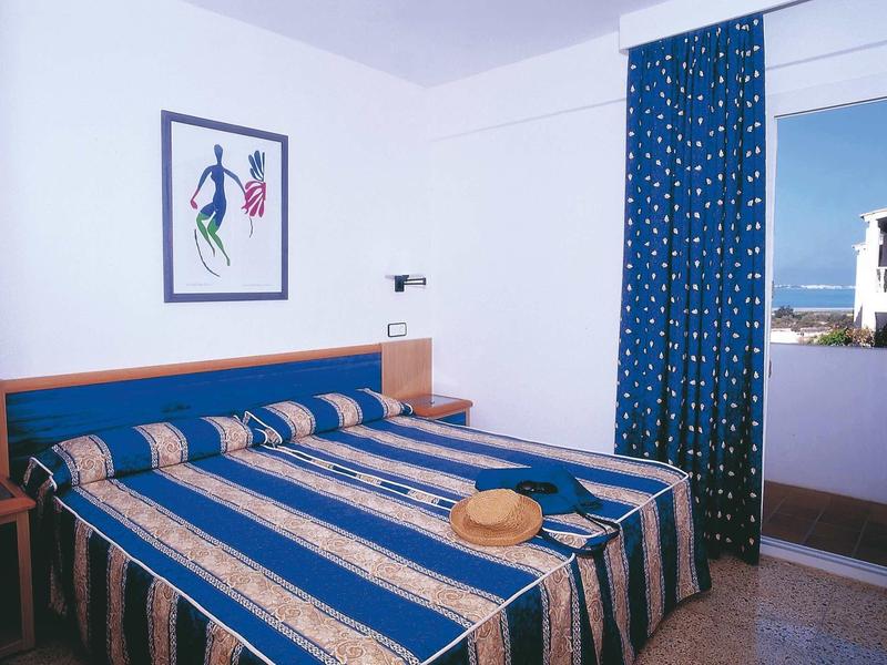 Ein einfaches, sauberes Schlafzimmer mit zwei nebeneinanderstehenden Betten und blauen Vorhängen.