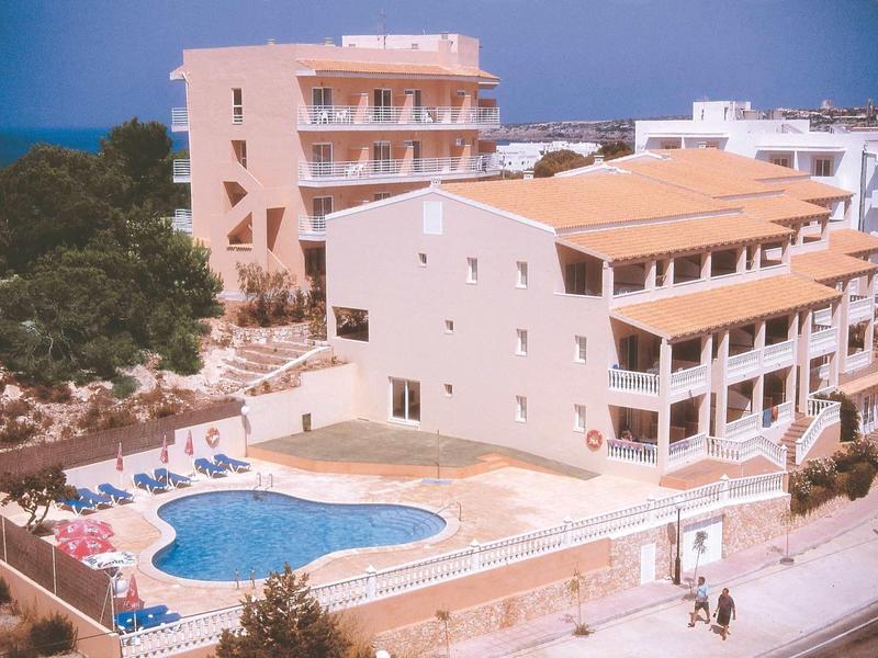 Hotel su più piani con piscina a forma di cuore, circondato da lettini e alberi.