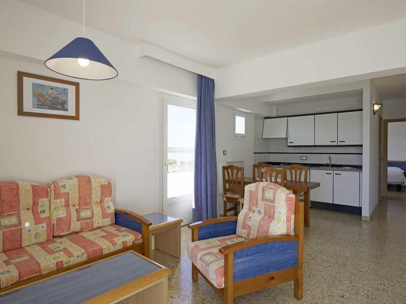 Area soggiorno accogliente con divano, poltrona, bancone cucina e vista sulle stanze adiacenti.