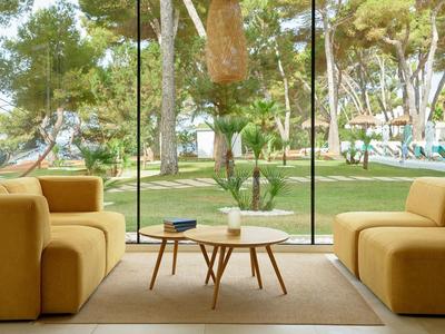 Lichte woonkamer met gele banken en uitzicht op tuin door grote glazen ramen