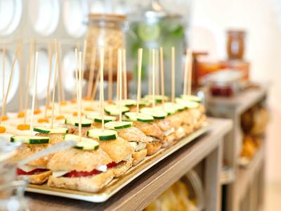 Reeks mini sandwiches met komkommerschijfjes en prikkers op een dienblad.