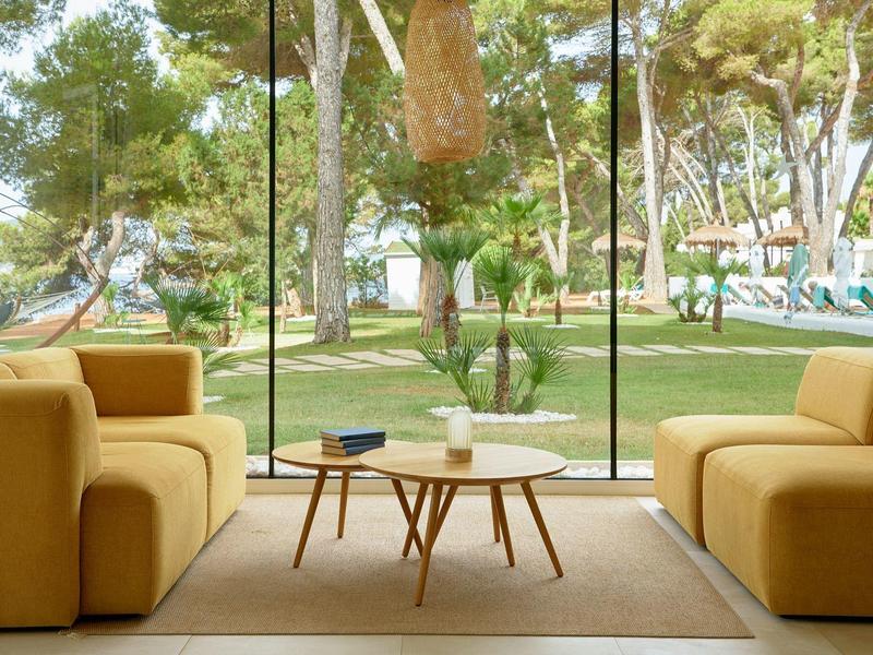 Lichte woonkamer met gele banken en uitzicht op tuin door grote glazen ramen