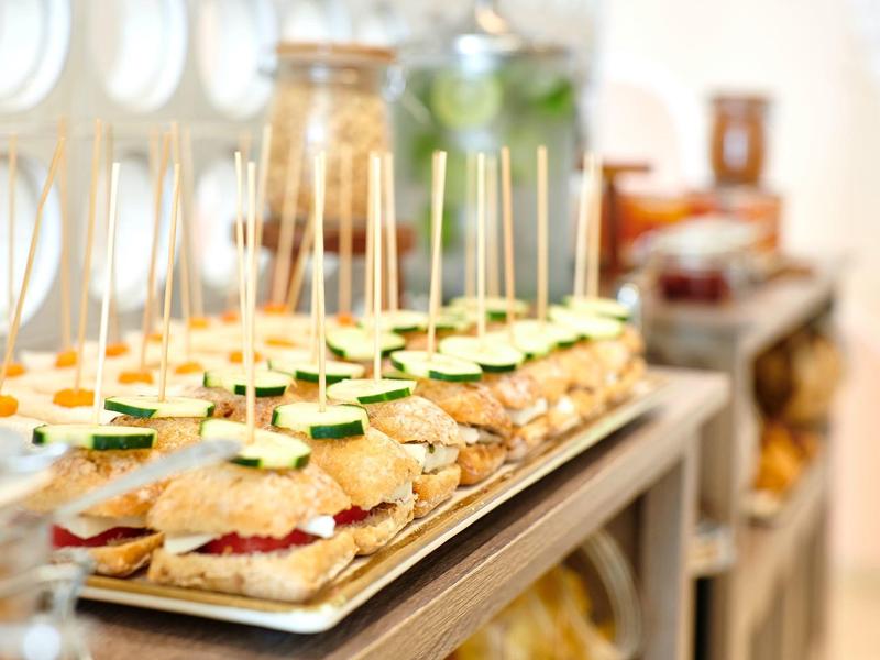 Reeks mini sandwiches met komkommerschijfjes en prikkers op een dienblad.