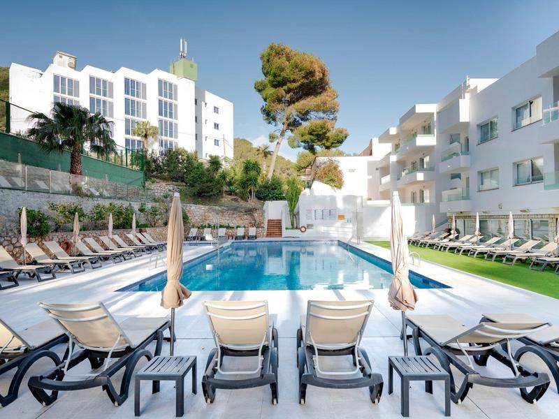 Modern hotel pool with lounge chairs and umbrellas under a clear sky.