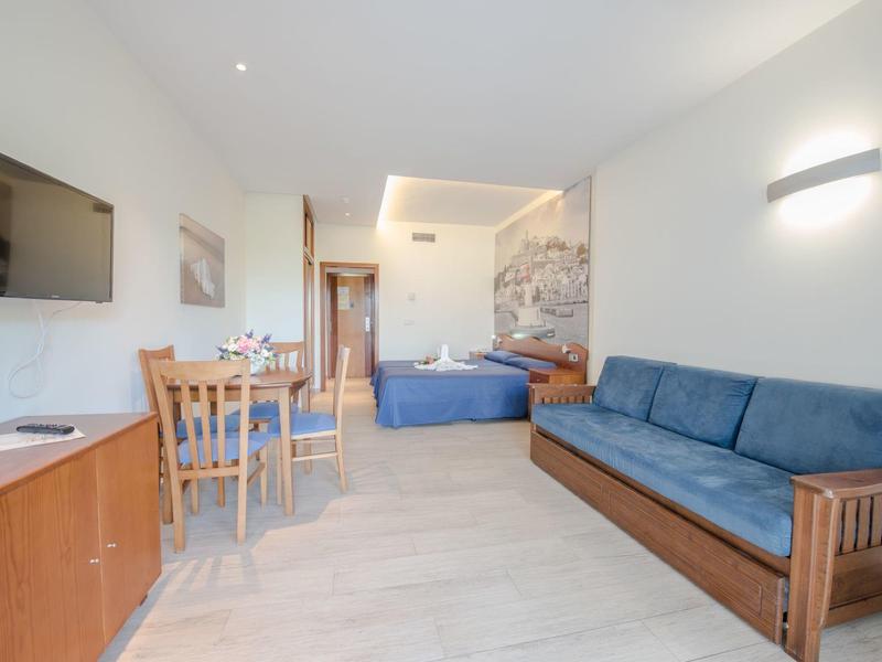 Bright hotel room with wooden furniture, blue sofa, and double bed in modern design.