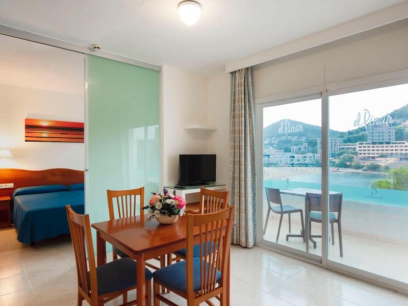 Modern hotel room with dining area, bed, and balcony with sea view.