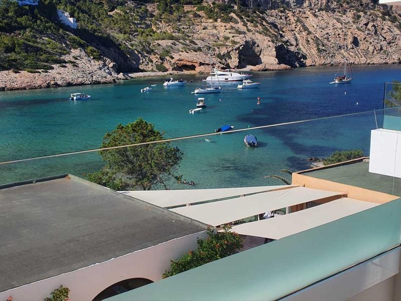 View of a calm bay with clear blue-green water from a balcony.