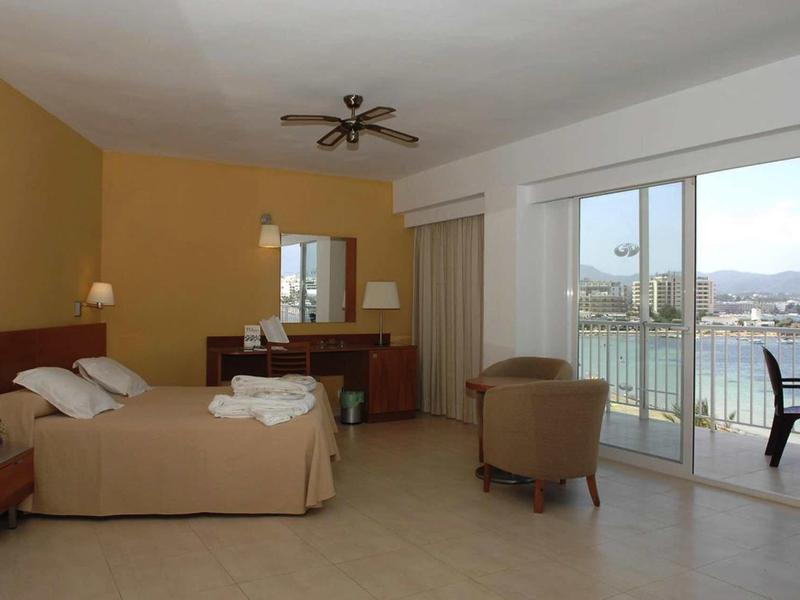 Prostorný pokoj s manželskou postelí, křeslem a balkonem s výhledem na moře.