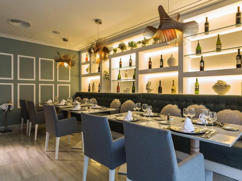 Elegantní jídelna s prostřeným stolem a modrými židlemi v moderním prostředí.