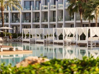 Modern hotel pool with white loungers and palm trees in the background on a sunny day