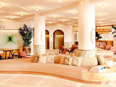 Modern hotel lobby with curved sofa area and artistic wall decor.