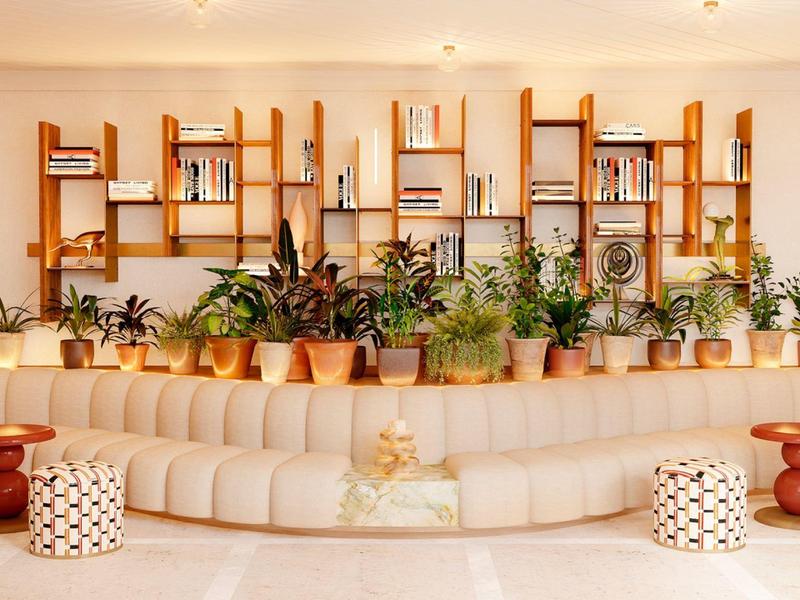 Modern waiting room with long cream sofa, wooden shelves, and numerous plants.