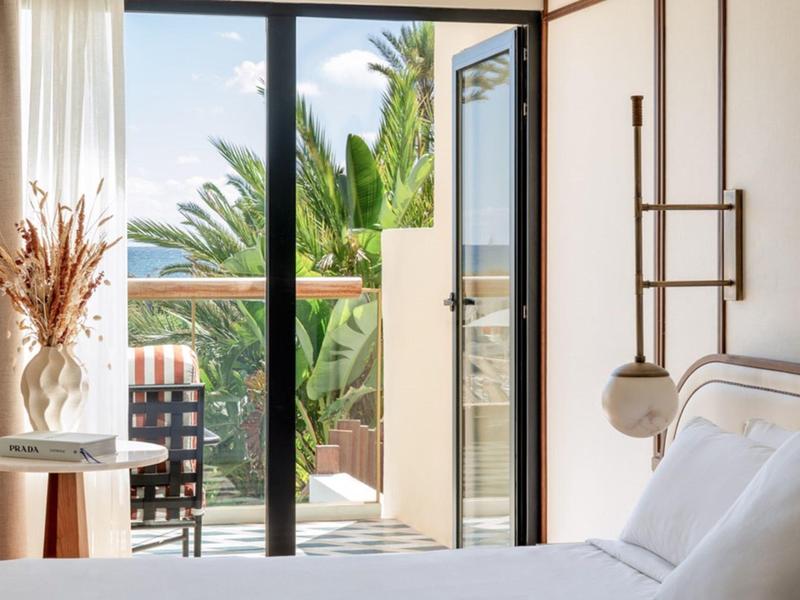 Bright bedroom with open balcony and view of palm trees