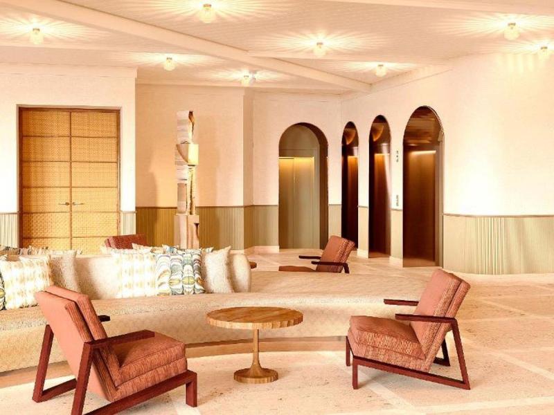 Elegant hotel lounge area with modern armchairs, table, and sofas in warm tones.