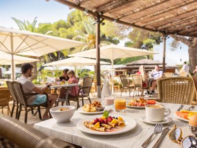 Tavolo per la colazione all'aperto con cibo e bevande sotto gli ombrelloni.