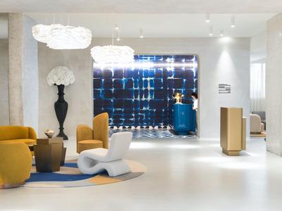Moderne hotellobby met stijlvolle stoelen, tapijt en decoratieve wandverlichting.